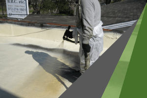A worker wearing gray protective clothing sprays on an elastomeric roof coating, which protects roofs from severe weather damage.